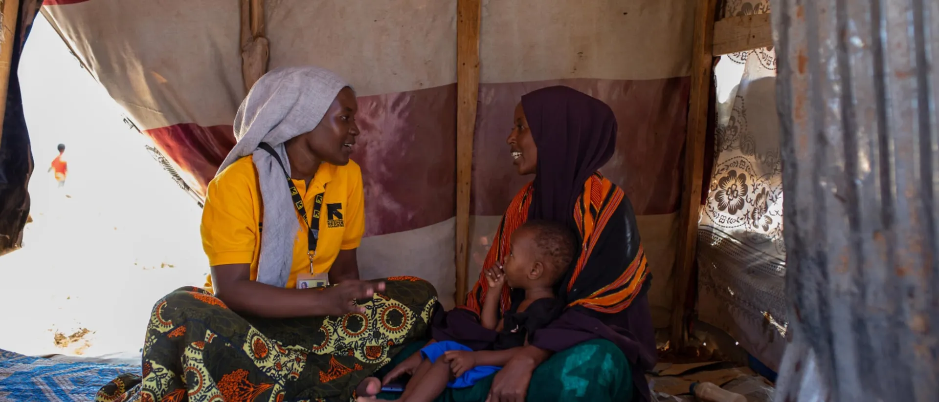 An IRC staff member speaking with a mother and child