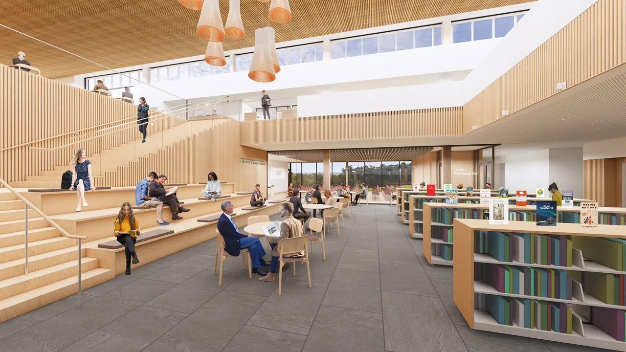 Sunlit modern interior of the Belmont Public Library, a Minuteman Library Network member, with patrons reading among bookshelves